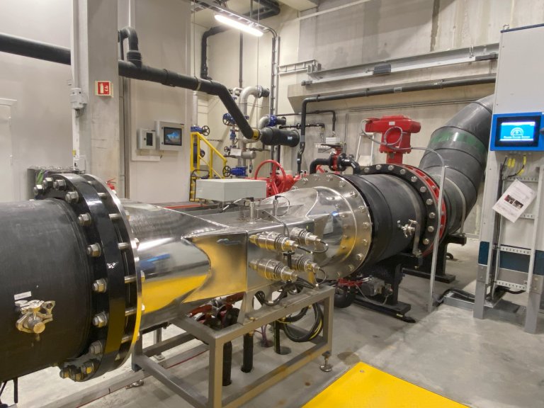 Desinfeksjon med UV med to prøvetakingspunkter – ett før og ett etter UV, og på veggen skjermen med styringssystemet (Intern kontroll) som viser parametere som UV transmisjon, dose, vannhastighet osv som blir registrert. Foto: Sonal Patel, Veterinærinstituttet